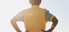 A boy in a yellow t-shirt faces away, looking off to the horizon