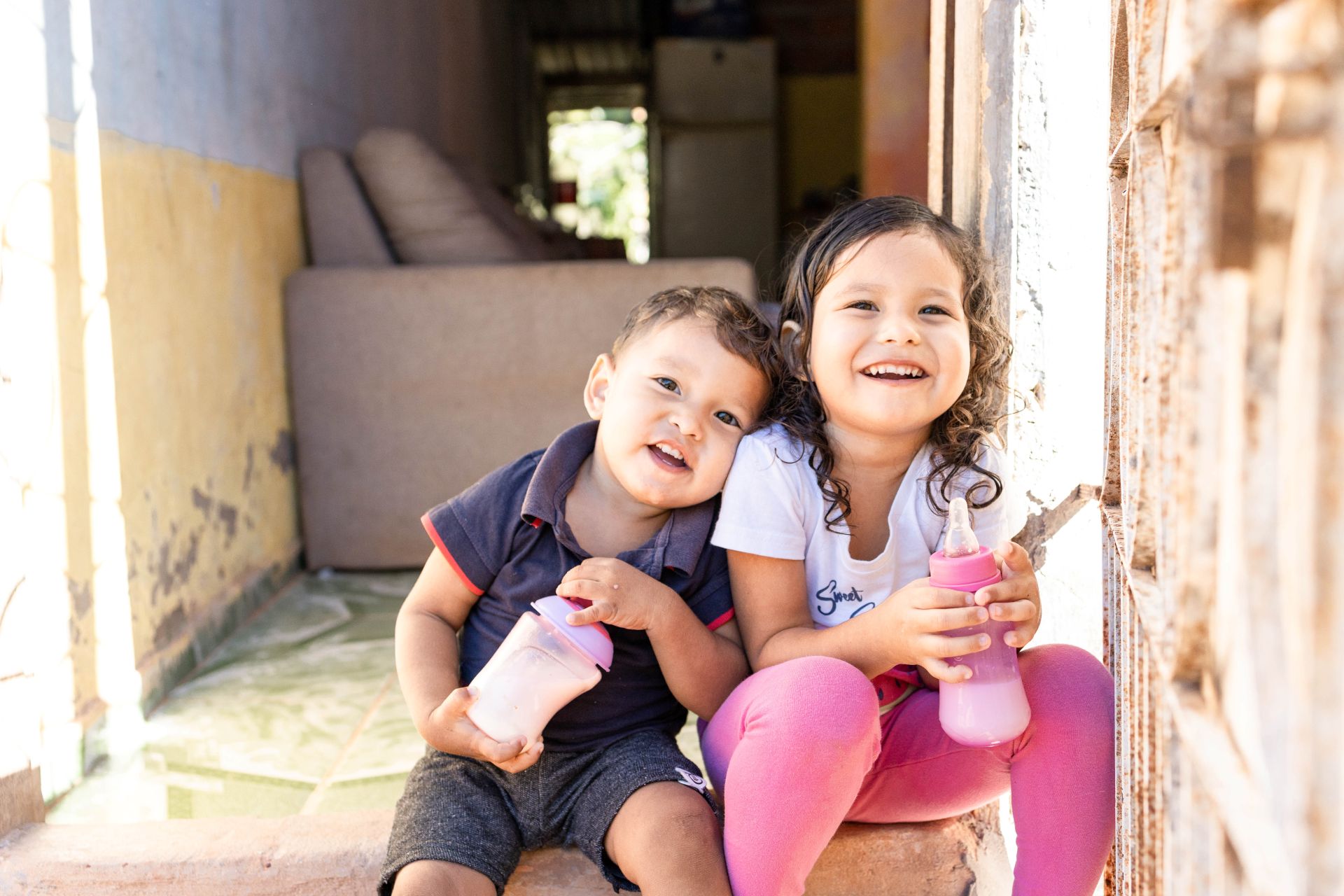 Close-up photo of a smiling mom holding her happy baby who is looking into the camera.
