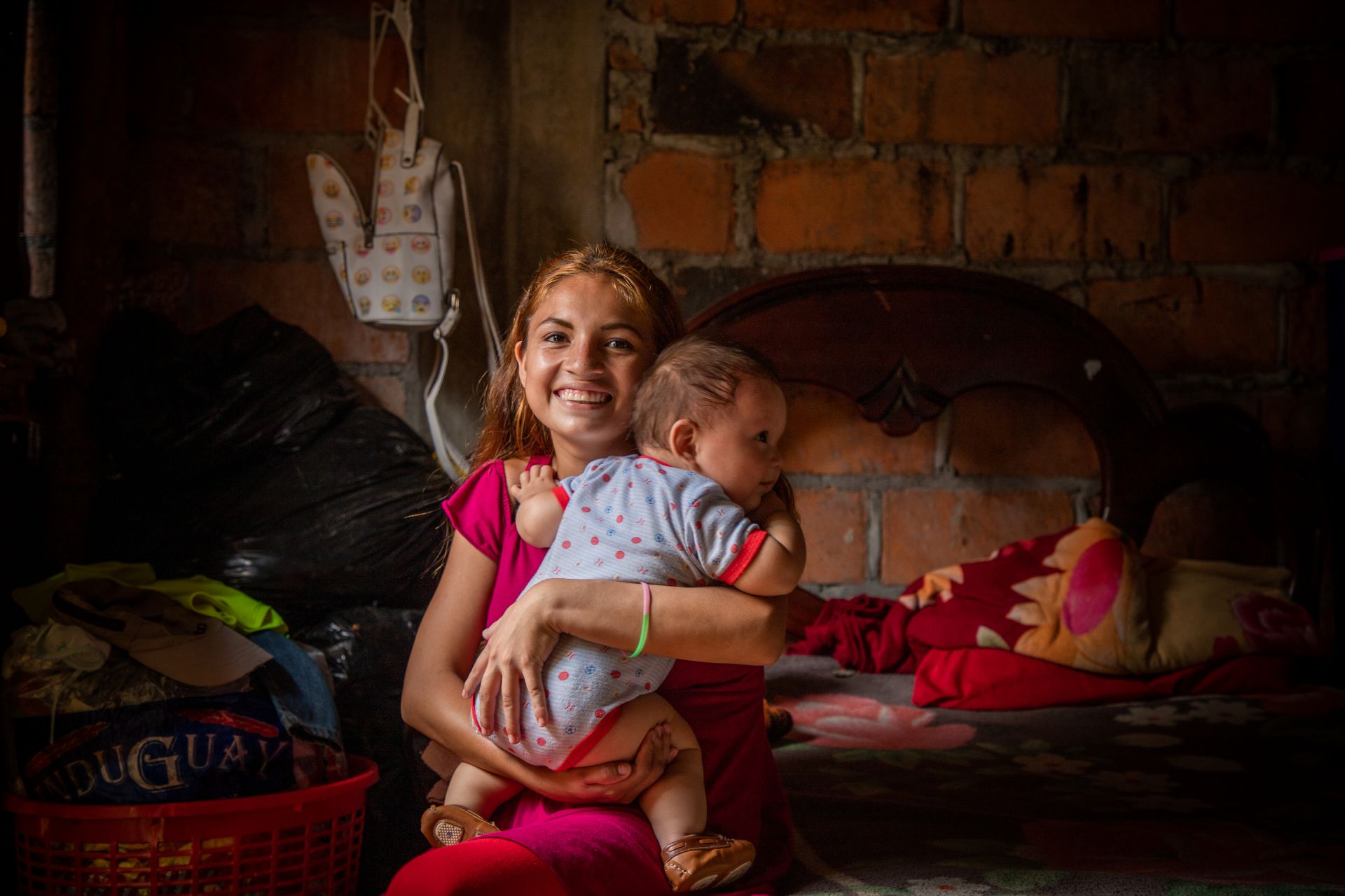 Smiling young mother looking into the camera while holding her baby in her arms.