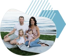 JAmes and April sit on a blanket infront of a lake with their two children.