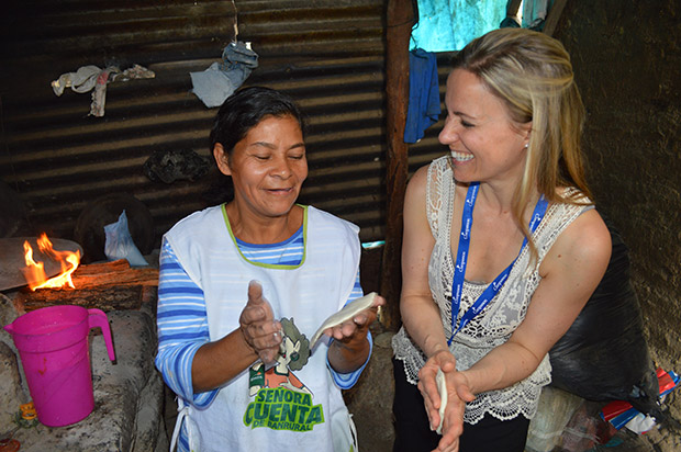 A visitor laughs as she makes tortilla with an older women.